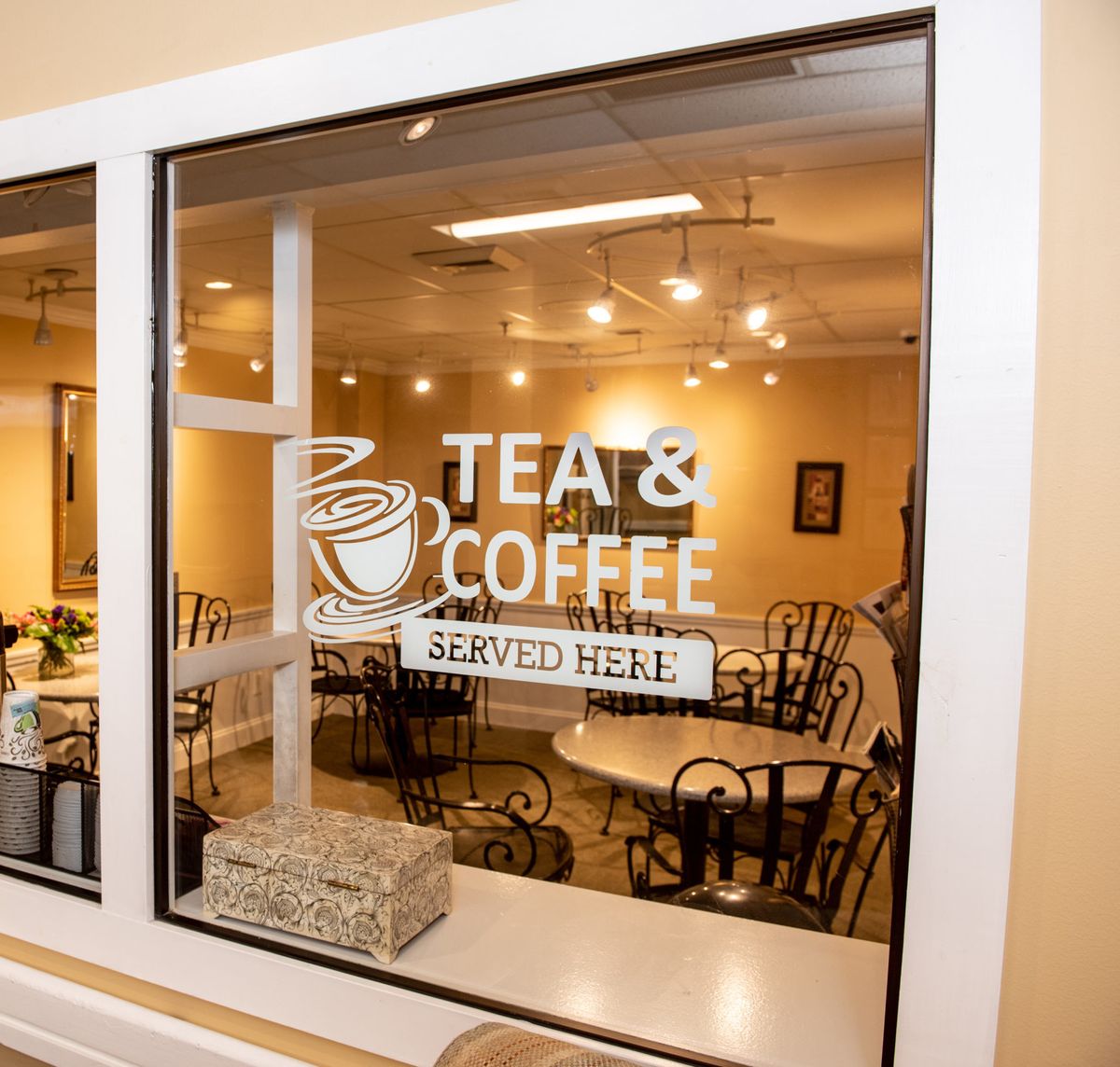 A cozy cafe interior with a sign showing 'Tea & Coffee Served Here.'