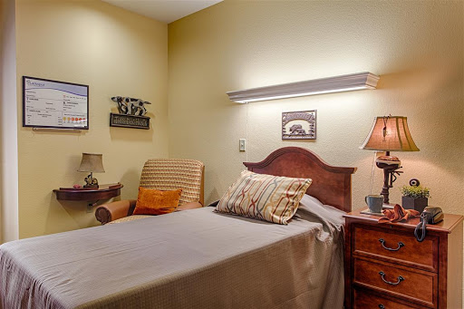 A cozy and inviting bedroom featuring a single bed, a comfortable chair, and warm lighting.