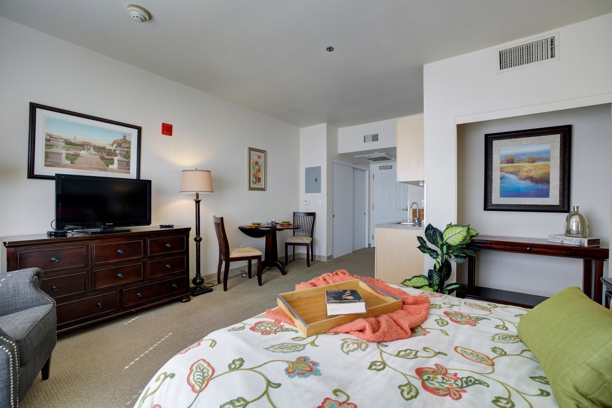 A cozy hotel room with a bed, television, and small dining area.