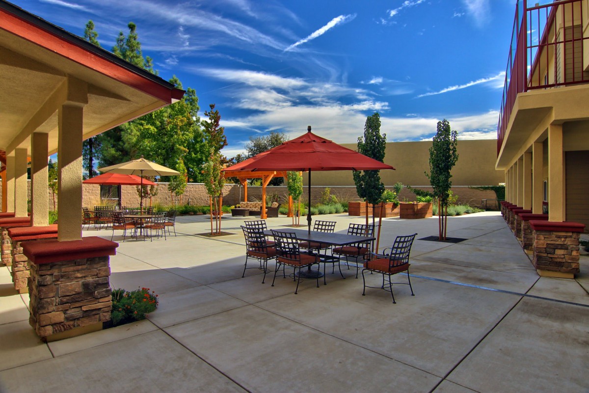 A sunny day on a patio with tables and umbrellas, set against a clear blue sky.