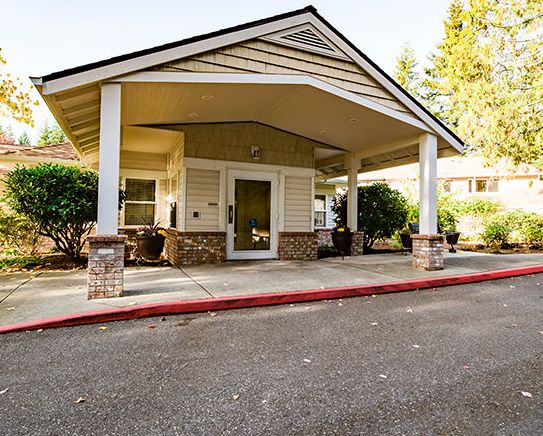 The entrance of a suburban building with a covered canopy and landscaped surroundings.