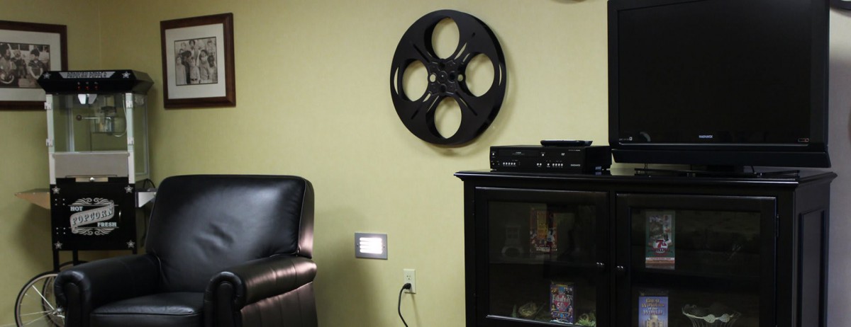 A cozy living room with a film reel wall decoration and a black cabinet.