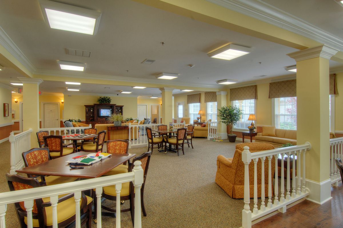 A spacious lounge area with tables, chairs, and a television.