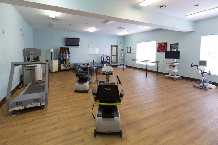 A spacious room equipped with exercise machines used for fitness and rehabilitation.