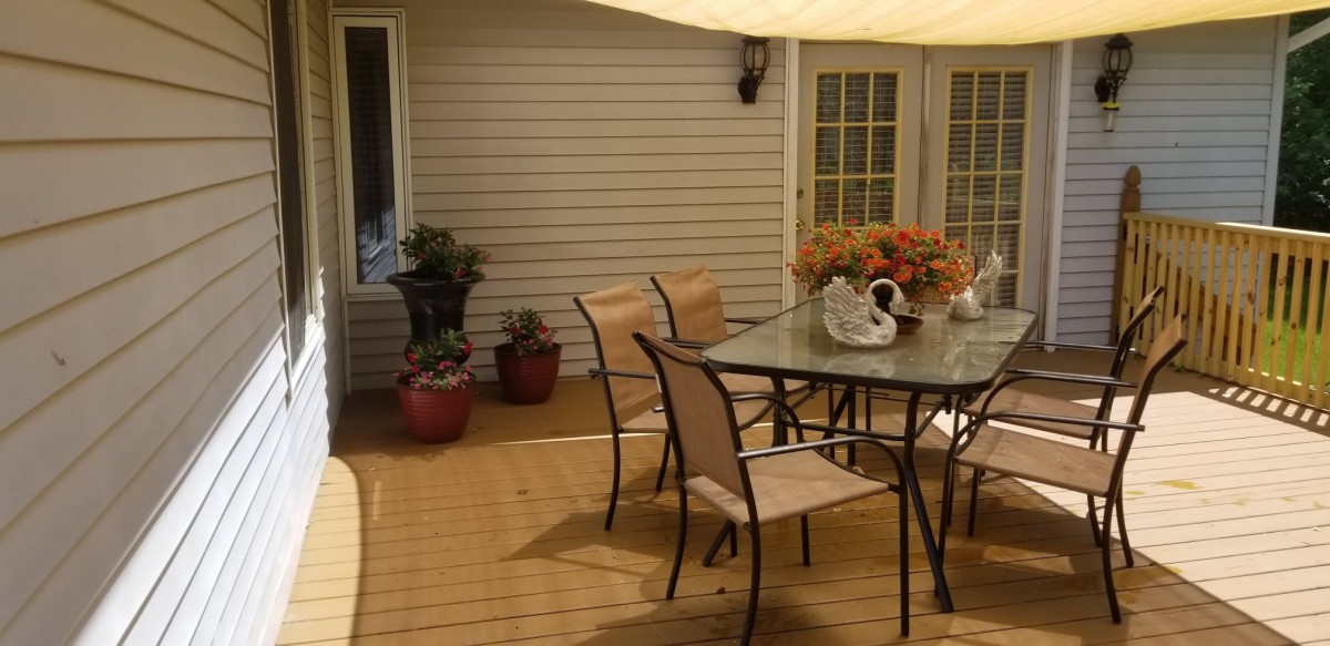 Cozy outdoor patio with a glass table, chairs, and potted plants.