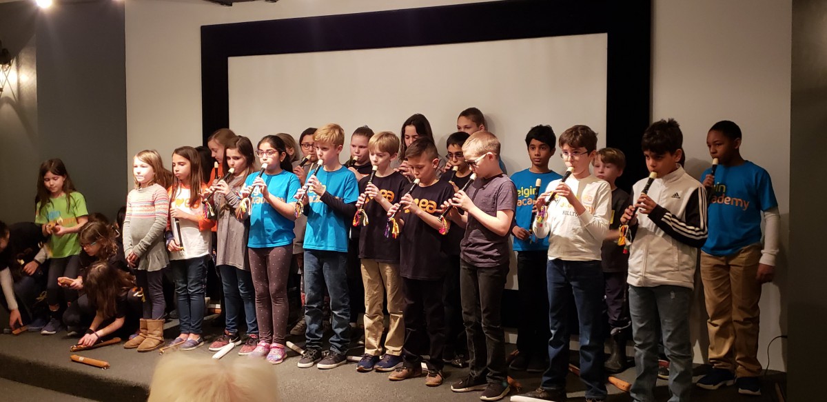 A group of children performing on stage with recorders.
