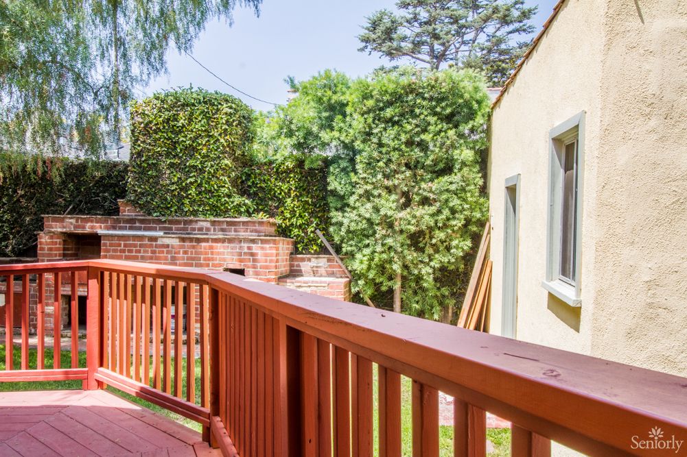 A sunny backyard with a wooden deck and lush greenery.