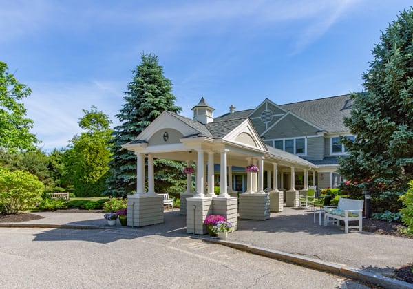 A sunny view of a large house with a grand entrance and well-maintained landscaping.