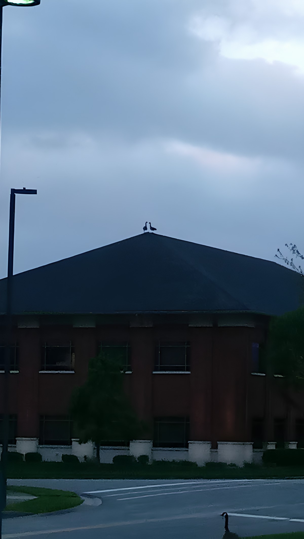 Silhouette of a building under a cloudy sky with two figures on the roof.