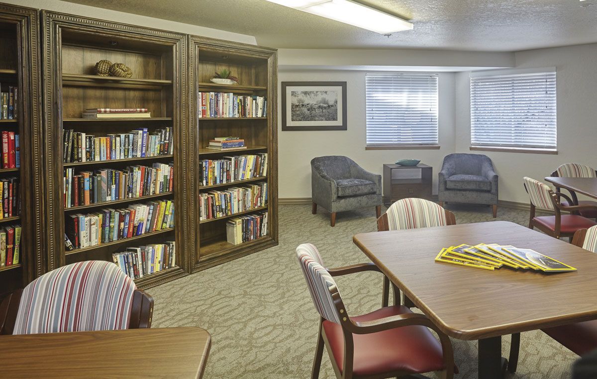 A cozy reading room with a bookshelf and comfortable seating.