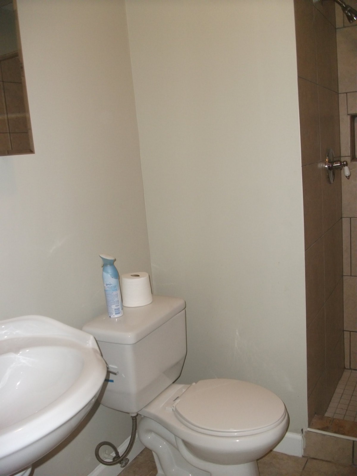 A minimalist bathroom featuring a sink, toilet, and shower.