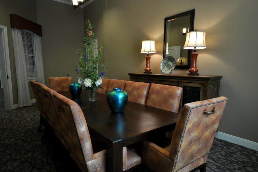 A beautifully decorated dining room with a dark wooden table, cushioned chairs, and elegant decor including vases and lamps.