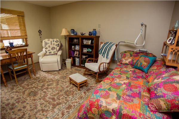A cozy bedroom with a colorful bedspread and armchairs.