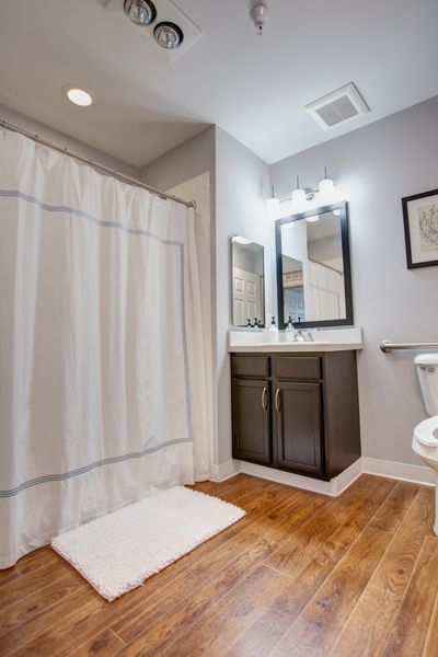 A modern bathroom featuring a shower with a curtain, dual mirrors above a sink, and a toilet.