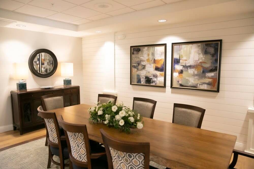 An elegant dining room with a wooden table, surrounded by chairs and decorated with abstract artwork.