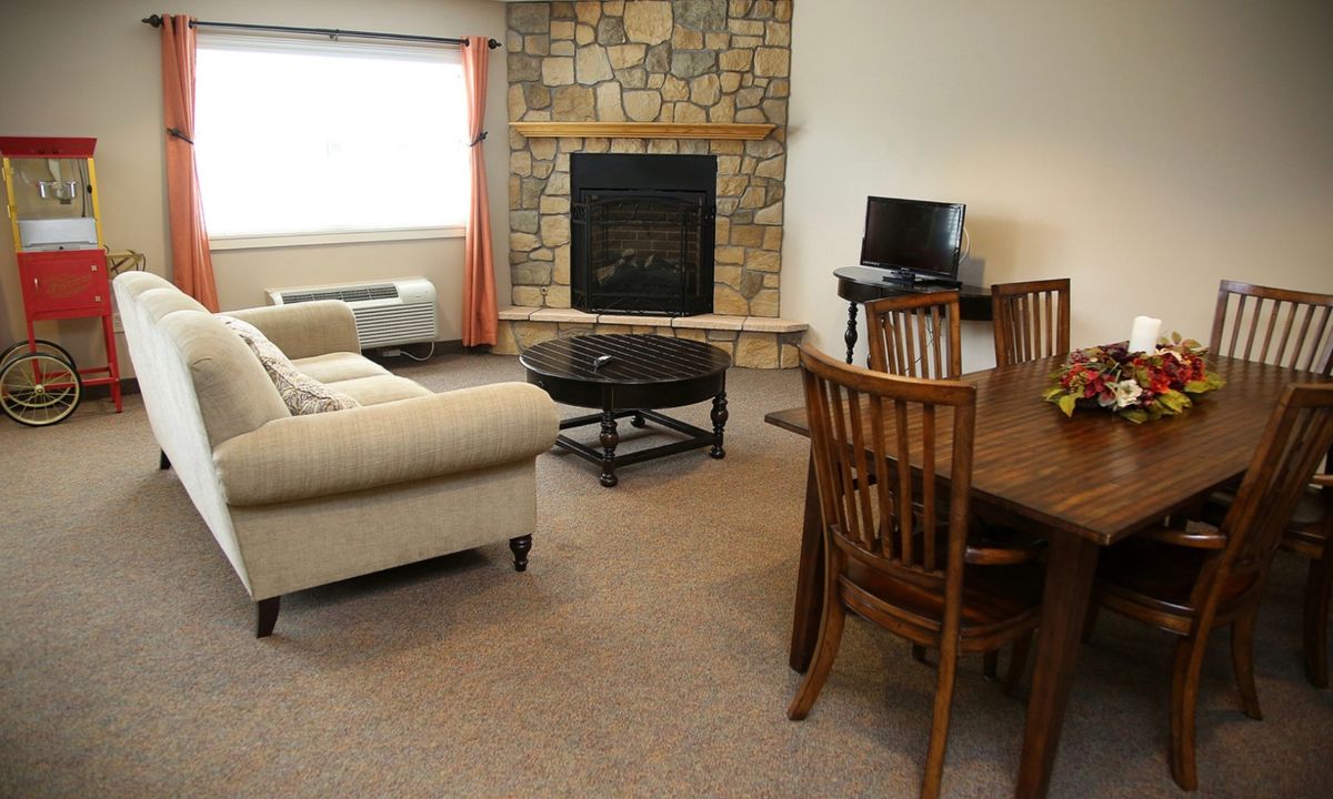 A cozy living room with a stone fireplace, comfortable sofa, and a dining area.