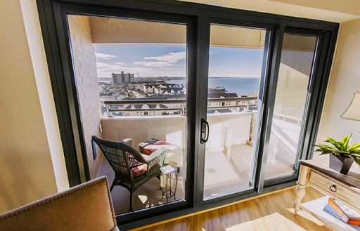 A serene balcony view overlooking the city and ocean, framed by modern glass doors.