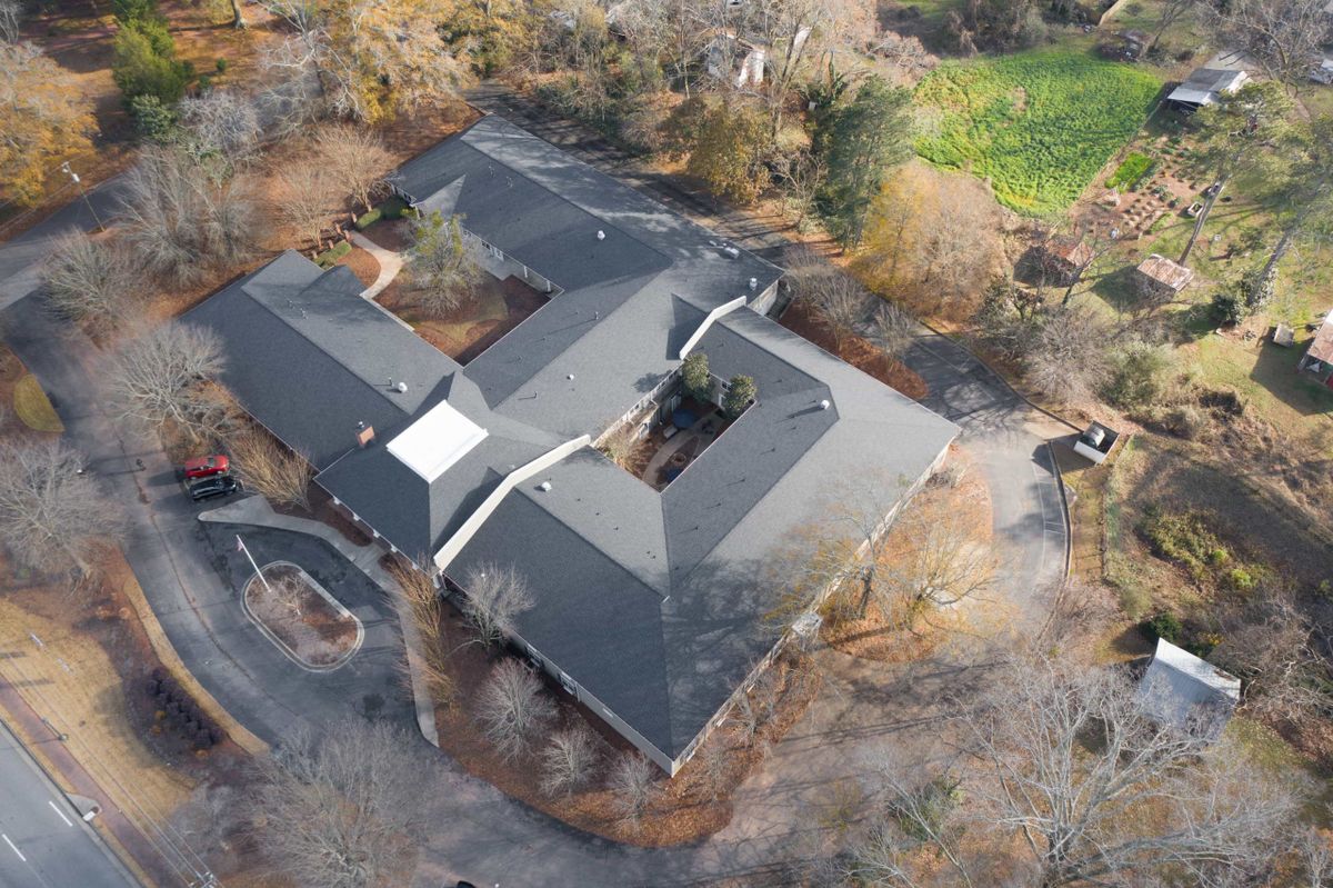 Aerial view of a large building surrounded by trees and natural landscape.