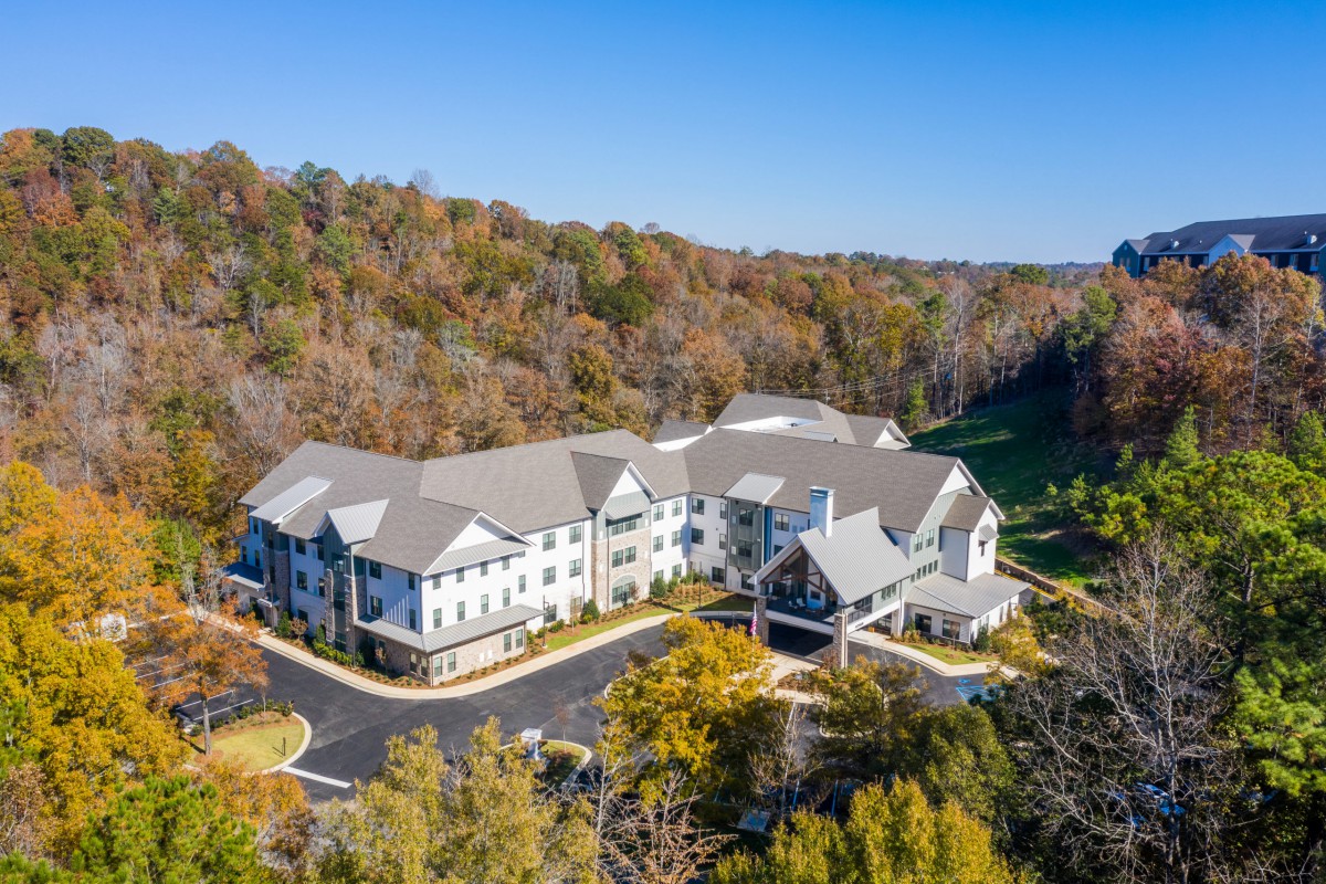 Aerial view of a large building surrounded by autumn trees and a parking lot.