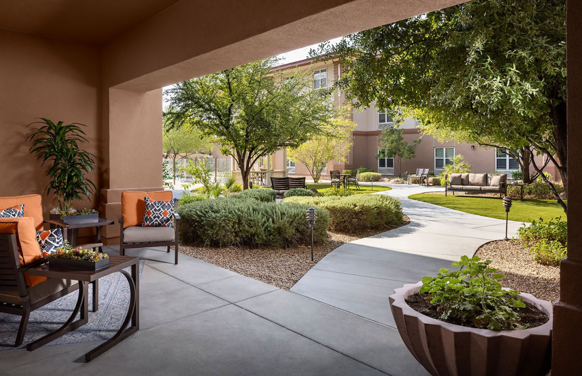 A peaceful outdoor patio with seating, surrounded by lush greenery and a well-maintained garden.