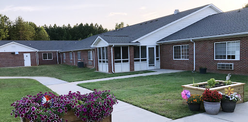 A serene view of a residential building surrounded by lush greenery and colorful flowers.