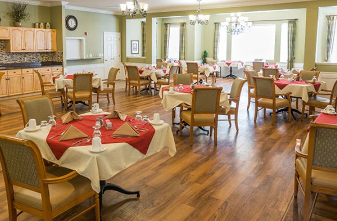 A spacious dining room with neatly set tables and wooden flooring.