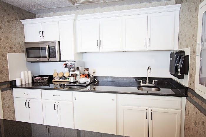 A modern kitchen with white cabinets and a granite countertop.