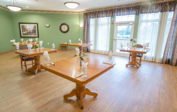 A neatly arranged dining area with wooden tables and chairs in a warmly lit room.