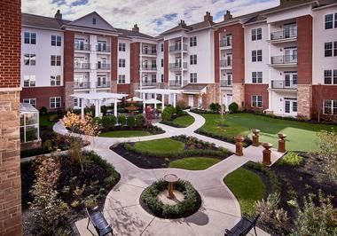 A beautifully landscaped courtyard surrounded by a multi-story apartment building.