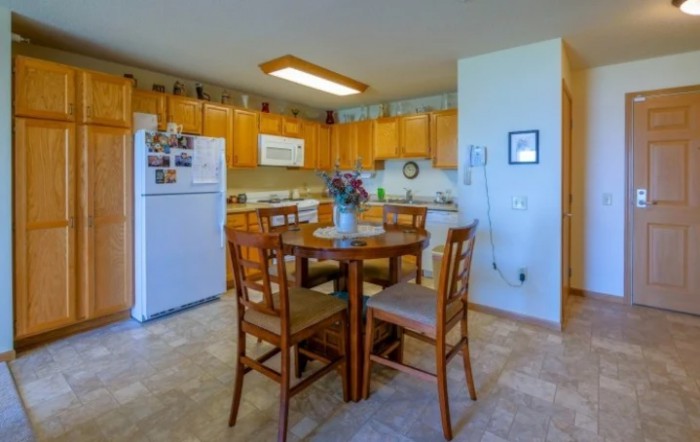 A cozy kitchen and dining area featuring wooden cabinets and a round table with chairs.