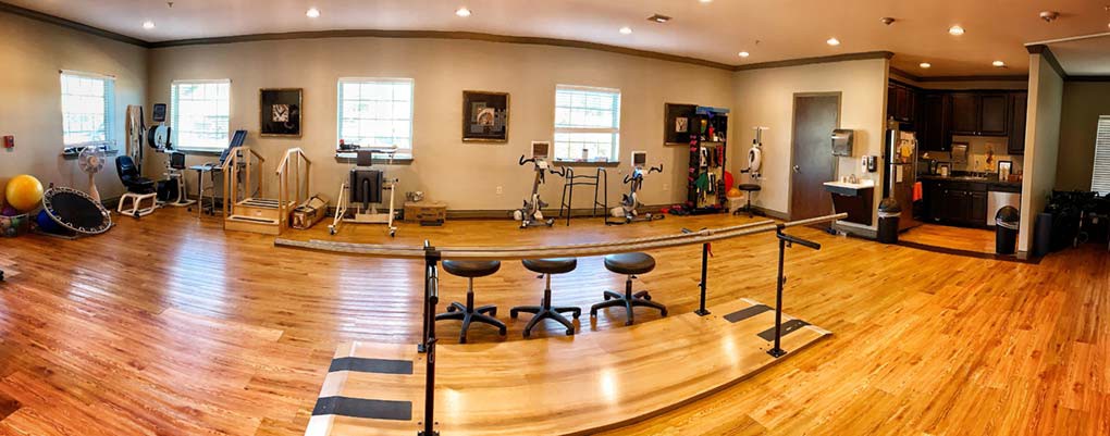 A physical therapy room equipped with exercise machines and seating for patient rehabilitation.