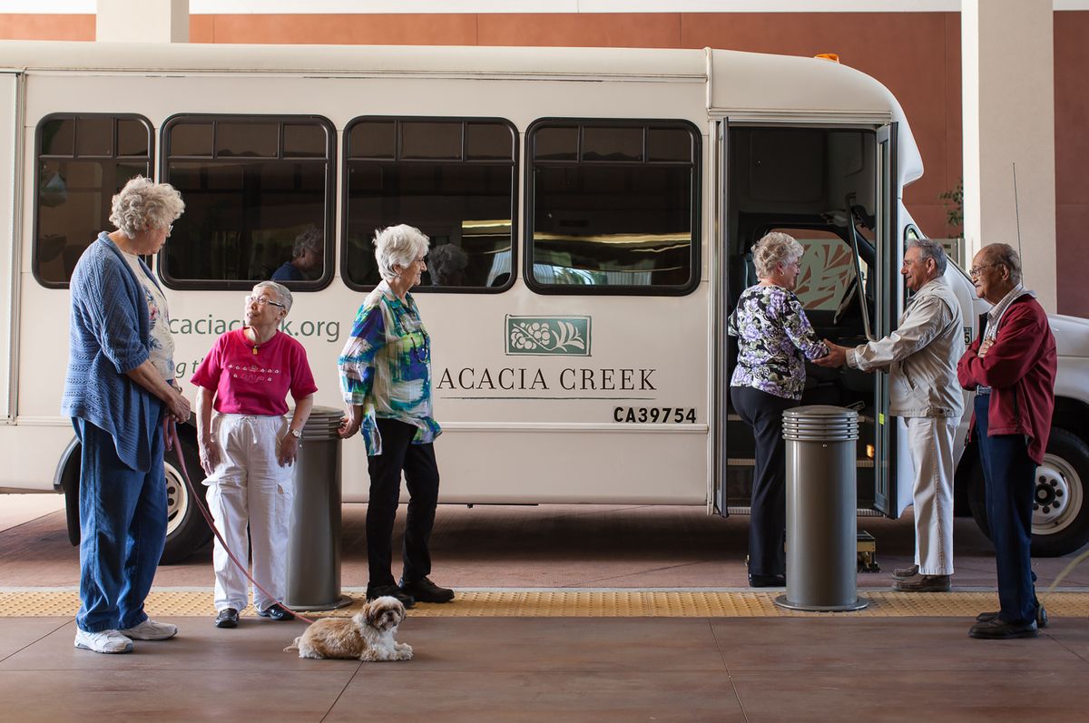 A group of elderly women and a dog in front of an Acacia Creek shuttle bus.