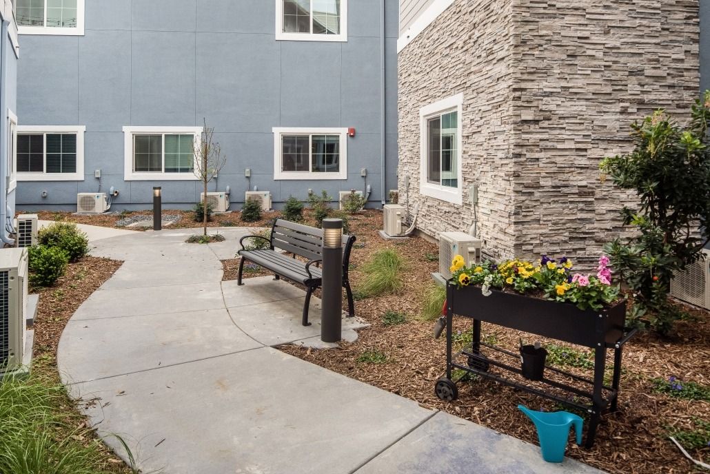 A peaceful courtyard with a bench, surrounded by landscaped greenery and potted flowers.