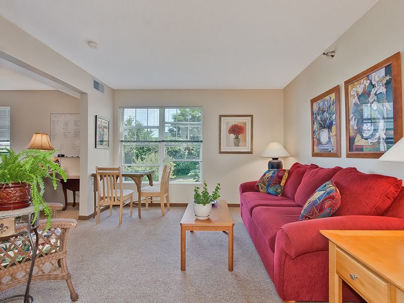 A cozy living room with a red couch, coffee table, and adjacent dining area.