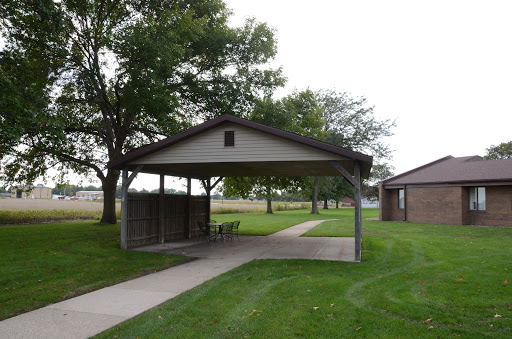 A serene park pavilion surrounded by lush green grass and trees.