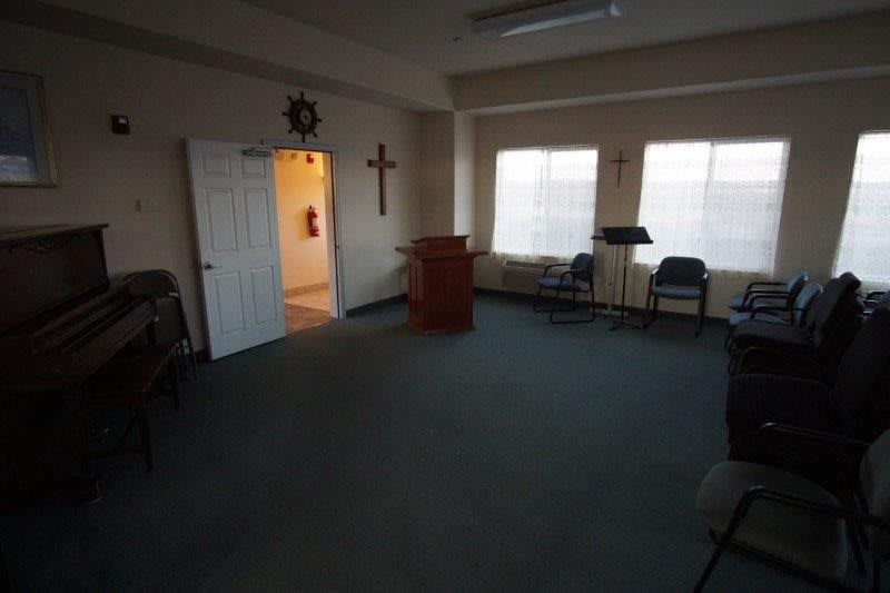 A small chapel room with a pulpit and chairs arranged around it.