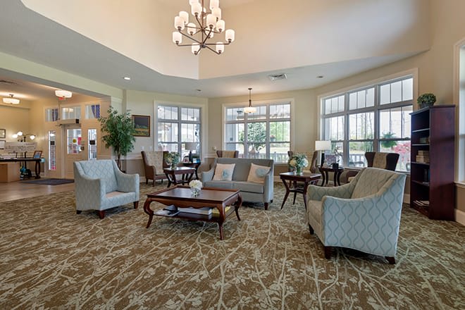 A spacious and elegantly decorated living room with comfortable seating and a central chandelier.