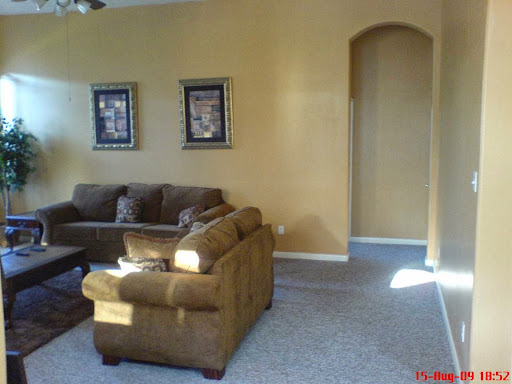 A cozy living room featuring a brown couch and decorative wall art on yellow-painted walls.