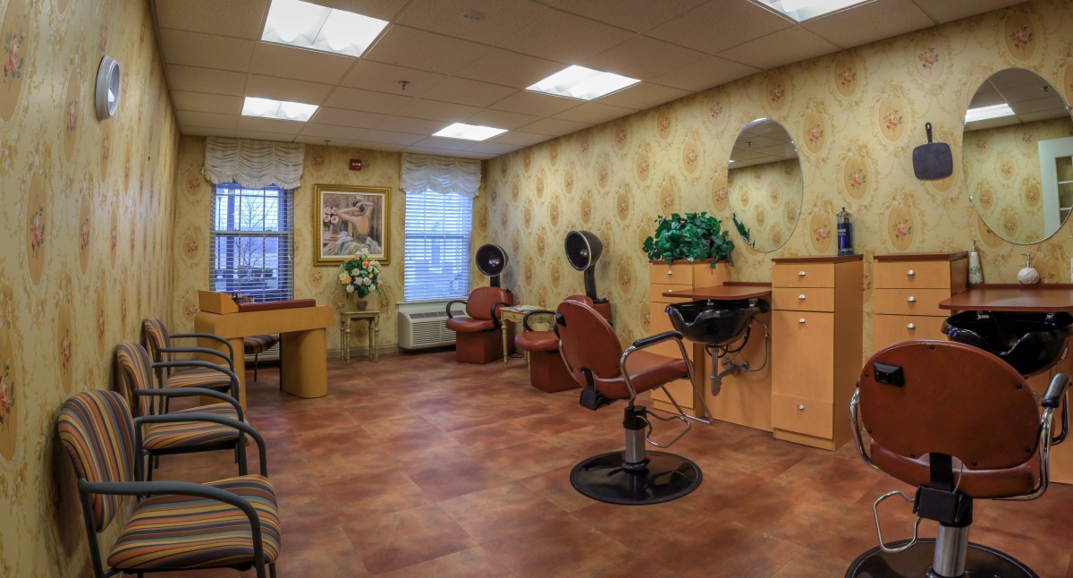 A spacious beauty salon interior featuring salon chairs, hairdryers, and a waiting area.