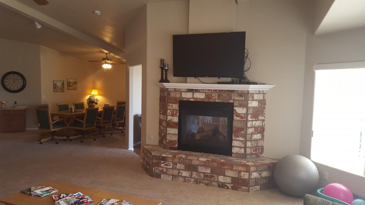 A cozy living room featuring a brick fireplace topped with a mounted TV.
