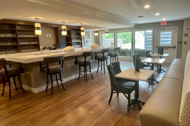 A modern bar and seating area with wooden flooring and stylish lighting.