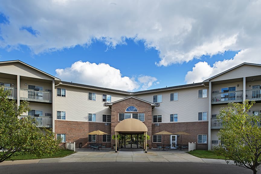 A multi-story residential apartment complex with a brick facade under a partly cloudy sky.