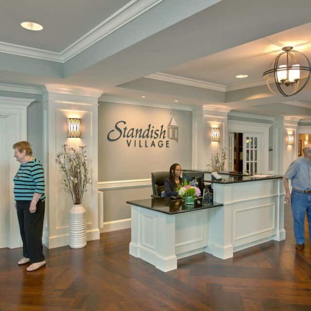 A welcoming reception area with a desk and people interacting in a well-decorated lobby.