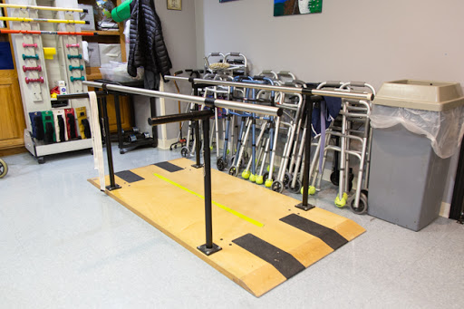 An exercise setup featuring parallel bars for rehabilitation and balance training, alongside various walking aids.