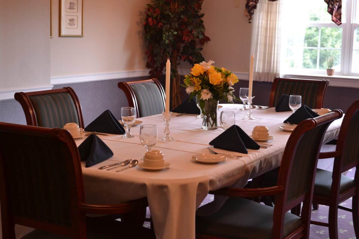 A formally set dining table with candles and a flower centerpiece.