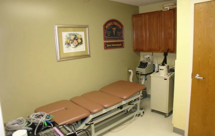 A medical examination room with a treatment table and various medical equipment.
