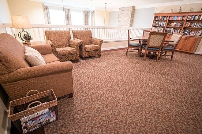 A cozy living room with comfortable chairs, a table, and a bookshelf.
