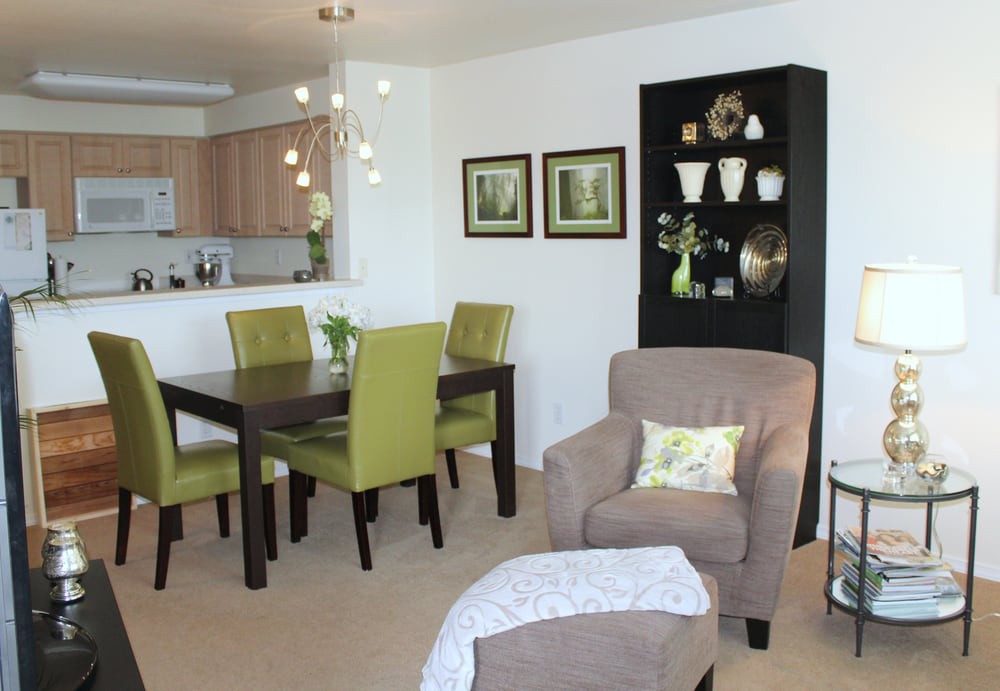 A modern open-plan dining and living area featuring green chairs and stylish decor.