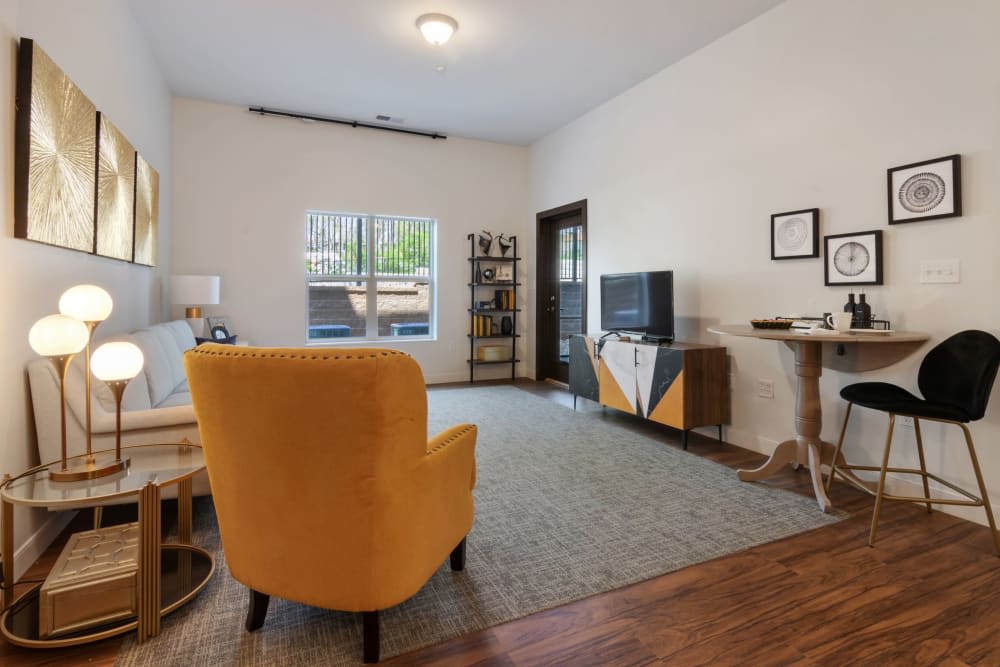 A modern living room featuring a vibrant yellow chair, hardwood flooring, and a sleek entertainment center with a TV.