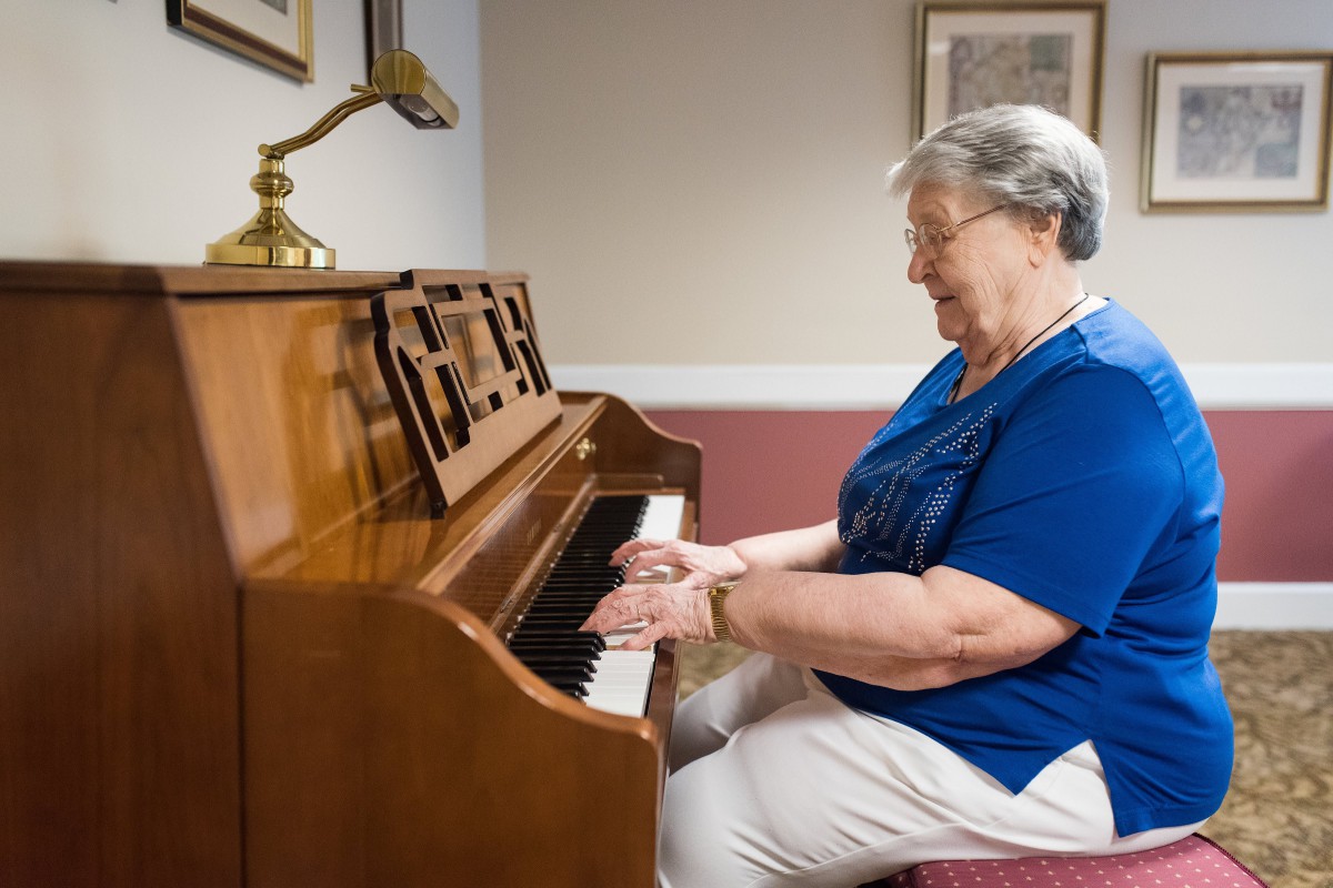 An elderly woman playing the piano indoors.